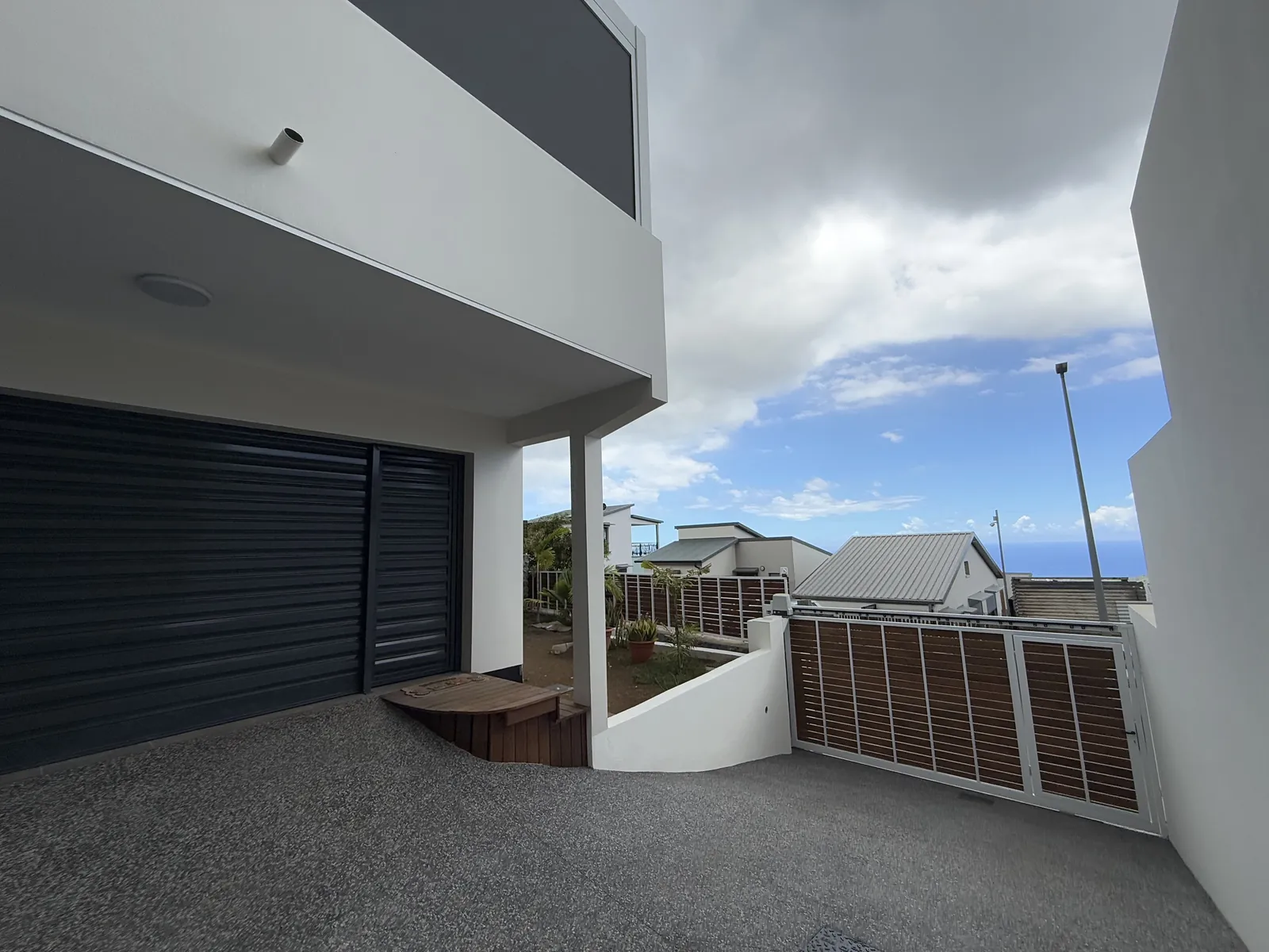Cour terminée en béton désactivé devant le garage, avec vue mer