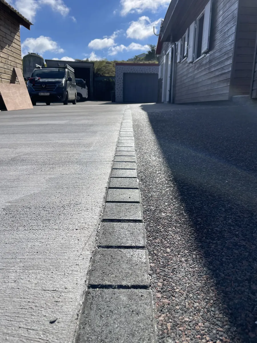 Caniveau posé entre la dalle balayée et la bande de béton désactivé
