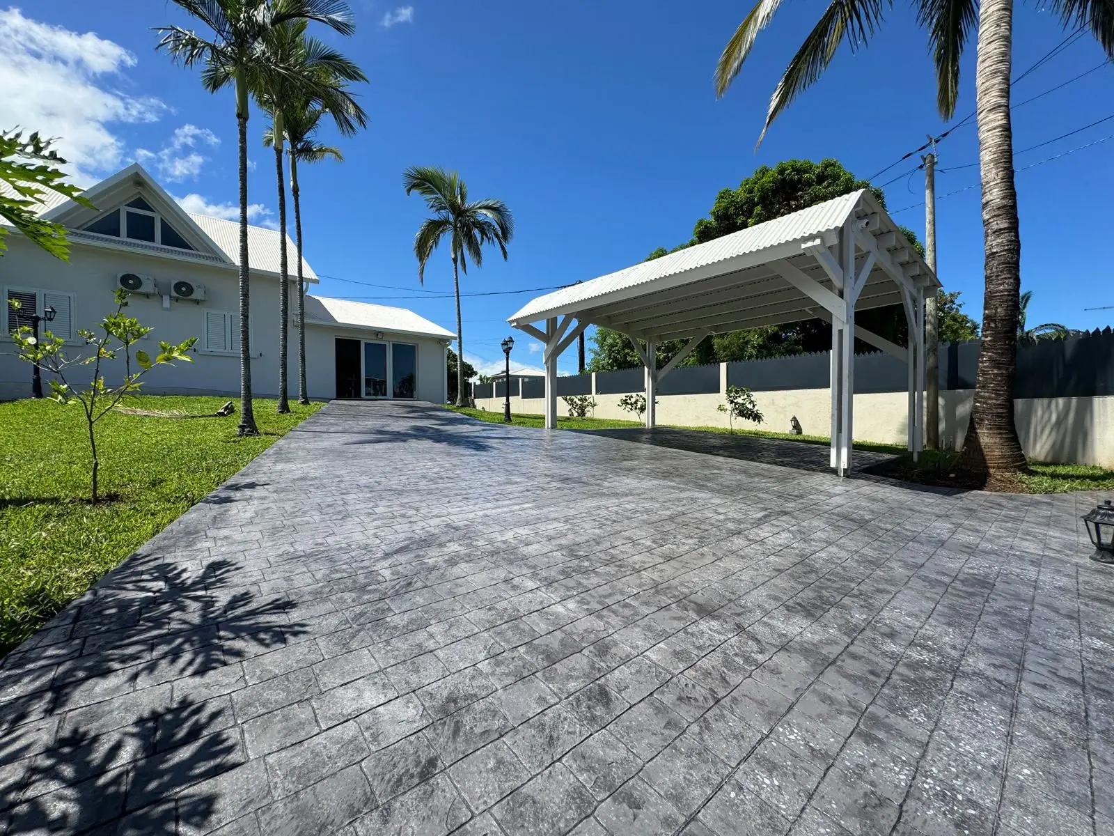 Grande allée carrossable en béton imprimé gris à motif dalle, sous les palmiers à La Réunion