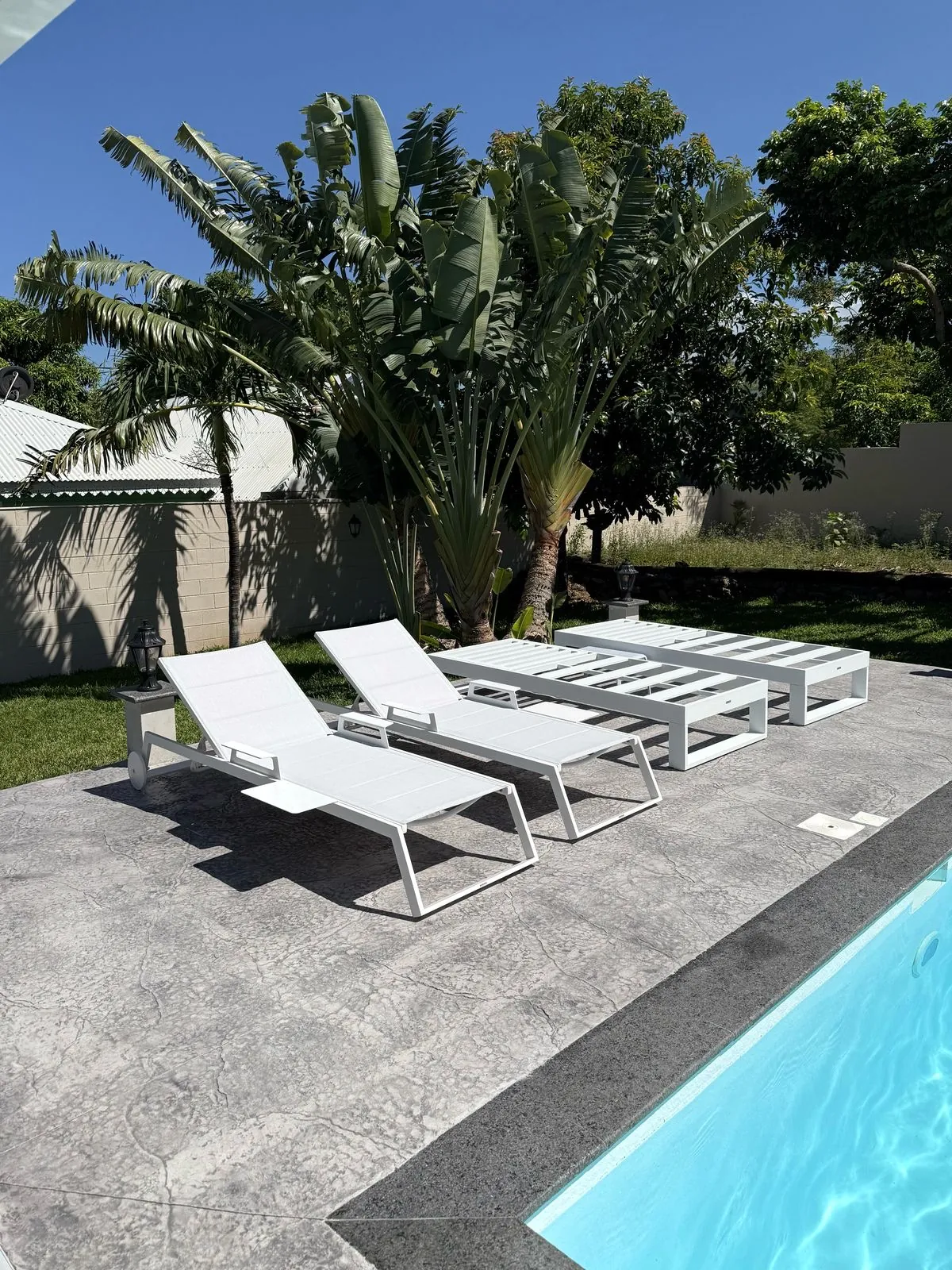 Plage de piscine en béton décoratif avec transats à La Réunion