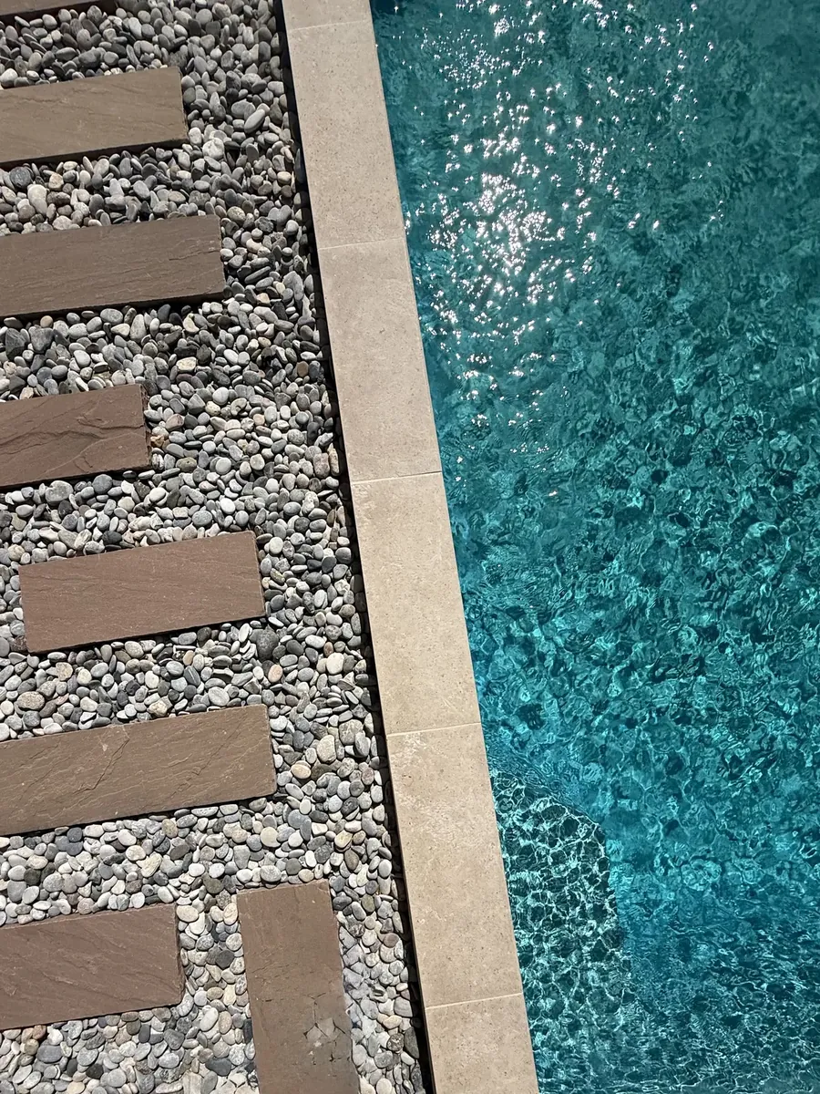 Pas japonais en bois et galets blancs le long d'une piscine, bordure claire